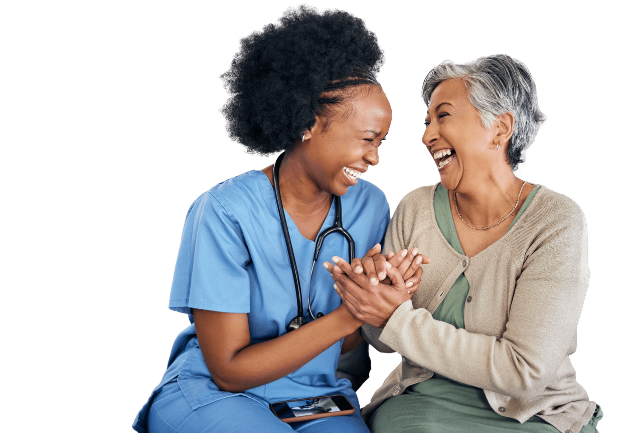 A healthcare worker in blue scrubs supports an elderly woman with a cane, both smiling
