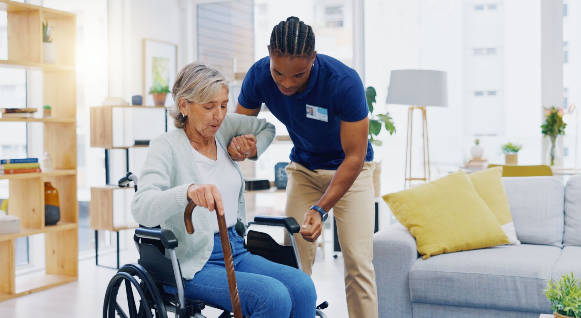 Caregiver assists a person using a wheelchair to stand Caregiver assists a person using a wheelchair to stand