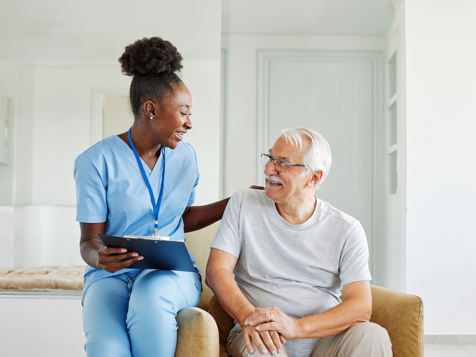 Woman points at document, smiling at older woman wearing glasses. Indoors, neutral tones. Woman points at document, smiling at older woman wearing glasses. Indoors, neutral tones.