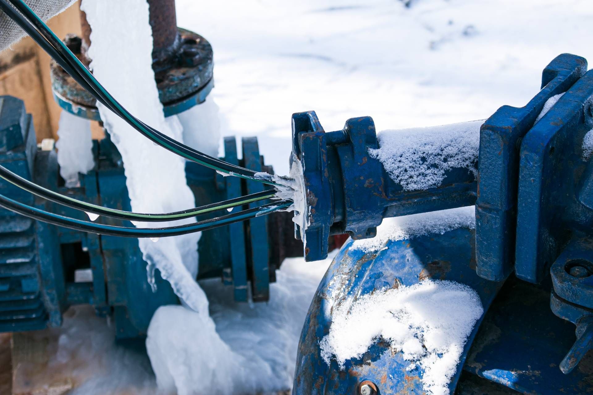 Tubi blu ghiacciati con ghiaccio e neve in un ambiente esterno.