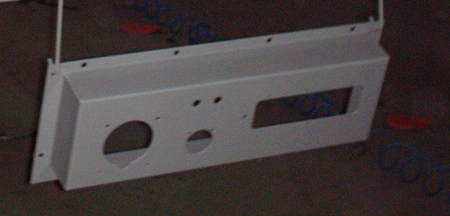 Cruscotto in metallo bianco con fori per indicatori e strumenti, sospeso.