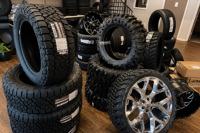 Stacked off-road tires and chrome wheels arranged on an automotive repair showroom floor in LaGrange Ga