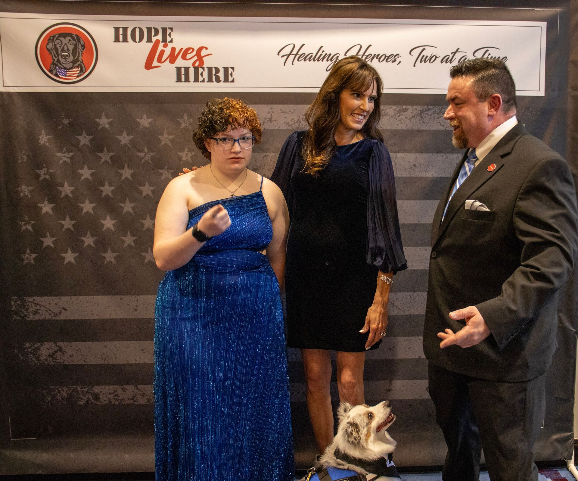 Three people and a service dog stand before a 