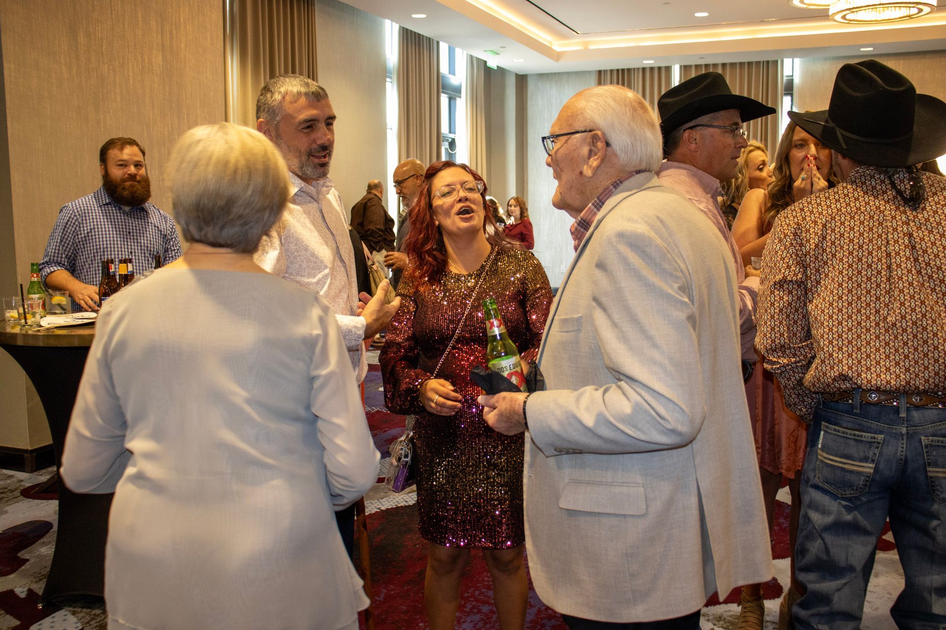 A group of people standing in a hotel ballroom, engaged in conversation at a social gathering.