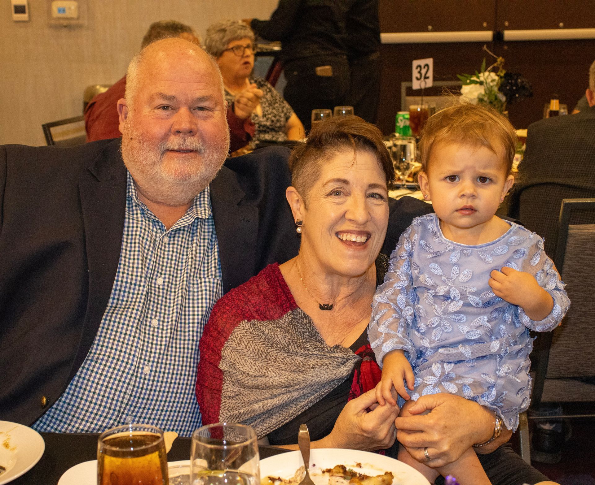 A man, a woman, and a child sitting together at a table in a dimly lit banquet hall.