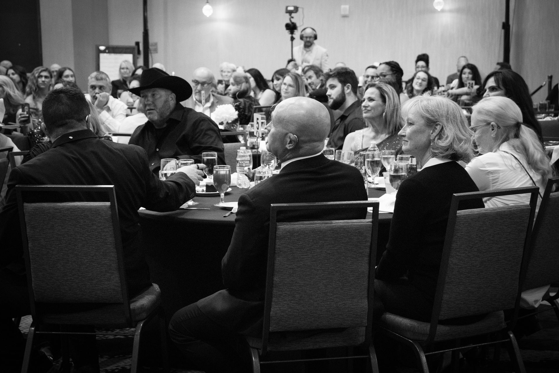 Attendees at a formal event seated at round tables for a banquet in a conference hall.