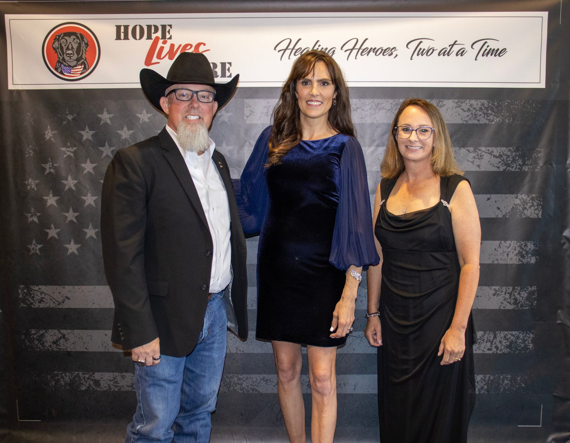 Three people stand before a banner for 