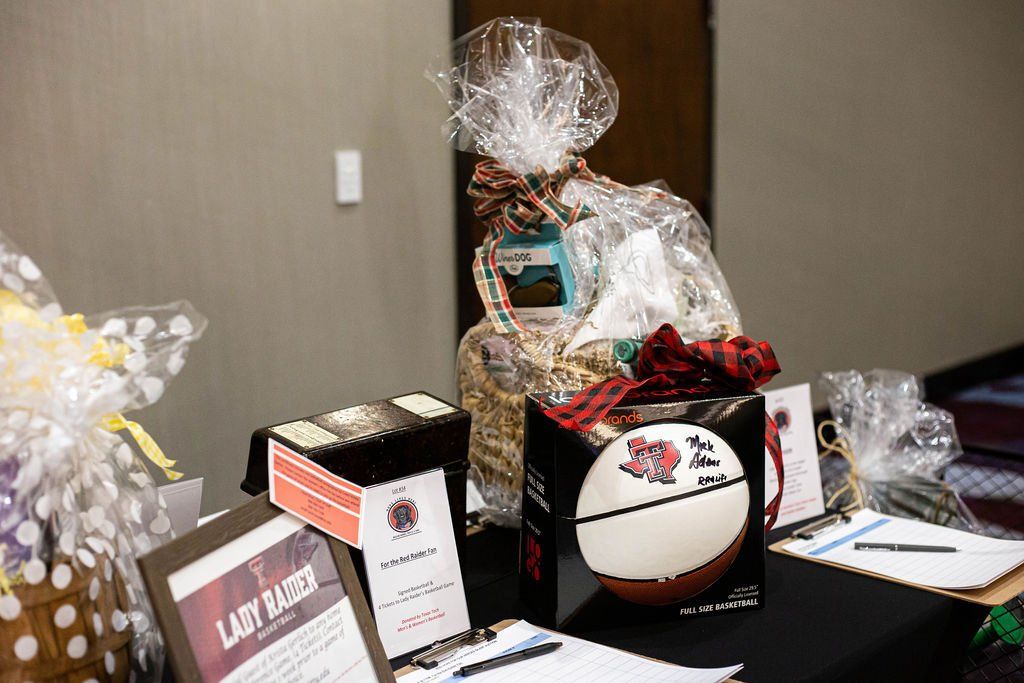 Gift baskets and informational signs arranged on a table for a silent auction or charity event.