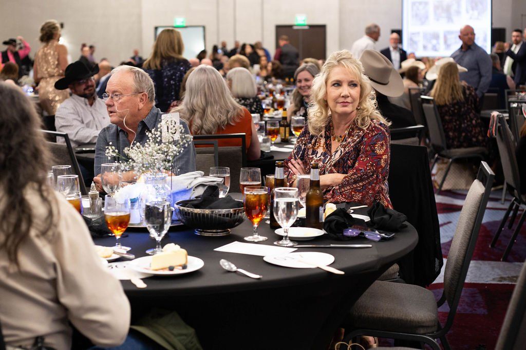 People seated at round tables in a banquet hall, enjoying dinner and conversation.