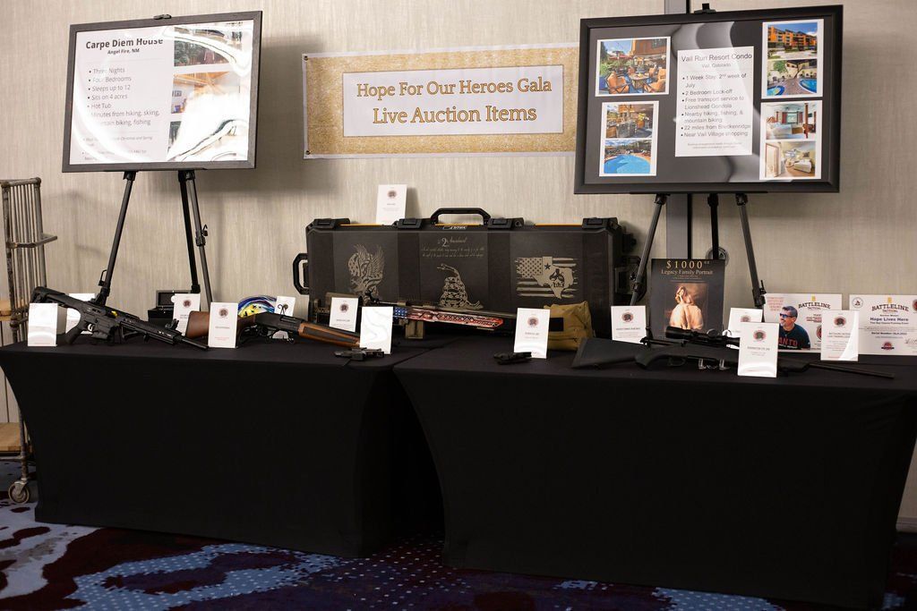 A table set up for a gala live auction with two display easels, auction items, and information cards on a black tablecloth.