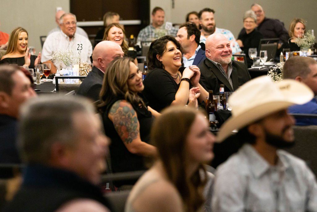 A group of people at a banquet hall, laughing and smiling while seated at tables during an event.