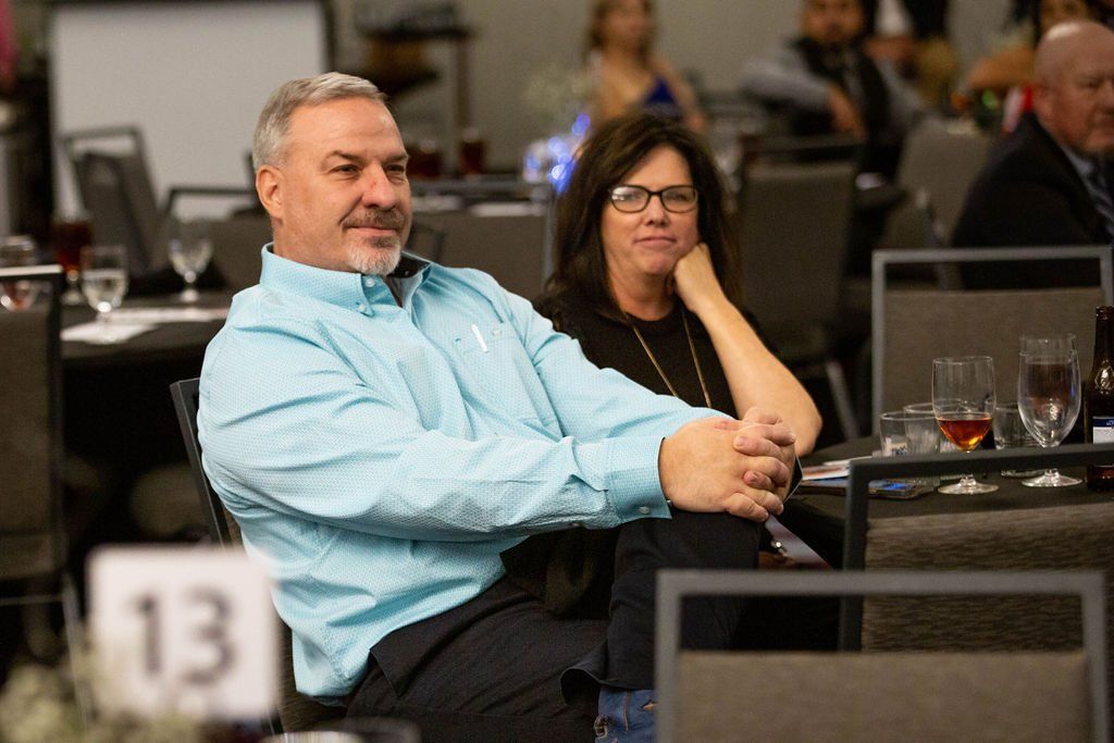 A man in a light blue shirt and a woman in a black top sit together at a table labeled 13 in a conference room.