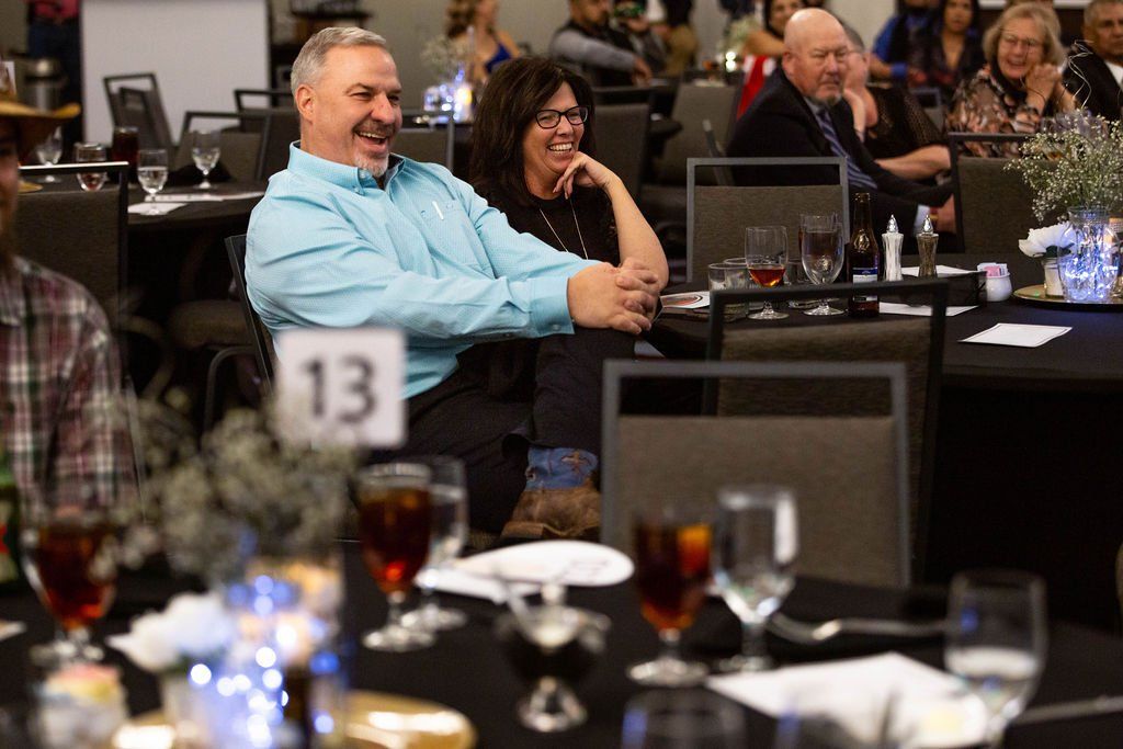 People laughing at a table at a banquet with place setting number 13 in the foreground.