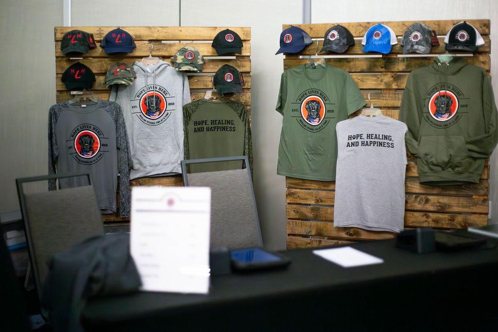 Display table featuring branded t-shirts, hoodies, and baseball caps mounted on two wooden pallet displays.