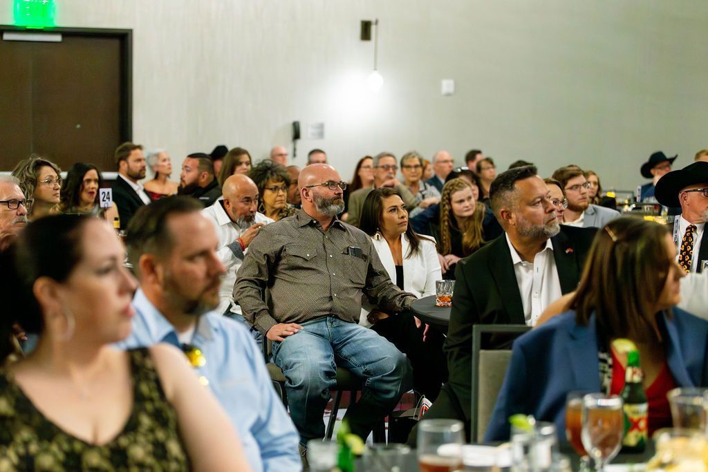 An audience sits attentively in a conference room, listening to a speaker during a professional event.