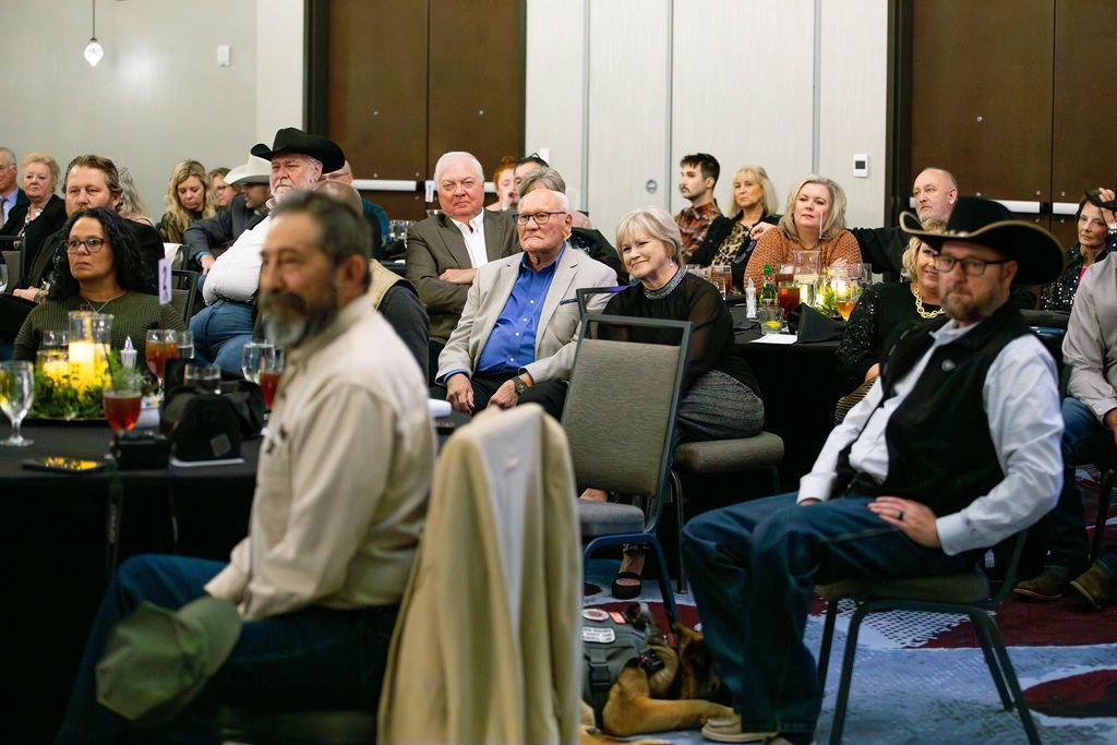 An audience seated at tables in a large conference room listening to a presentation.