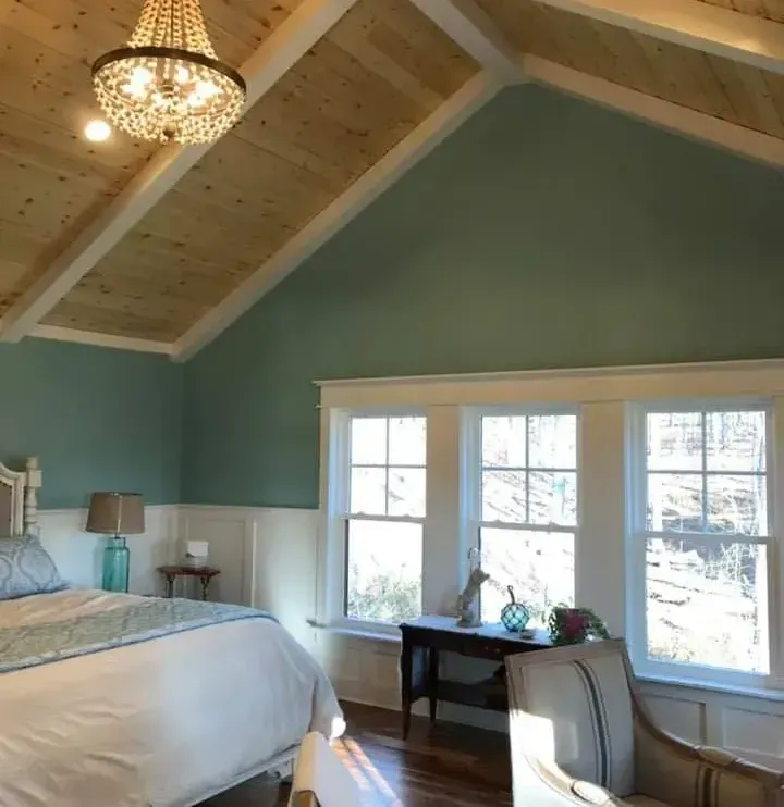 Bedroom with a wood plank ceiling, turquoise walls, and a white-framed window.
