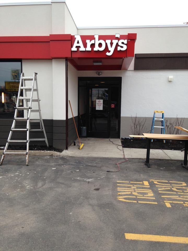 Arby's restaurant entrance; construction equipment present, including ladders and tables. Red and white building exterior.