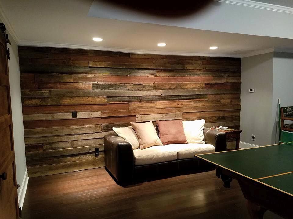 Living room with wood-paneled wall, couch with pillows, and a pool table. Dark wood flooring and recessed lighting.