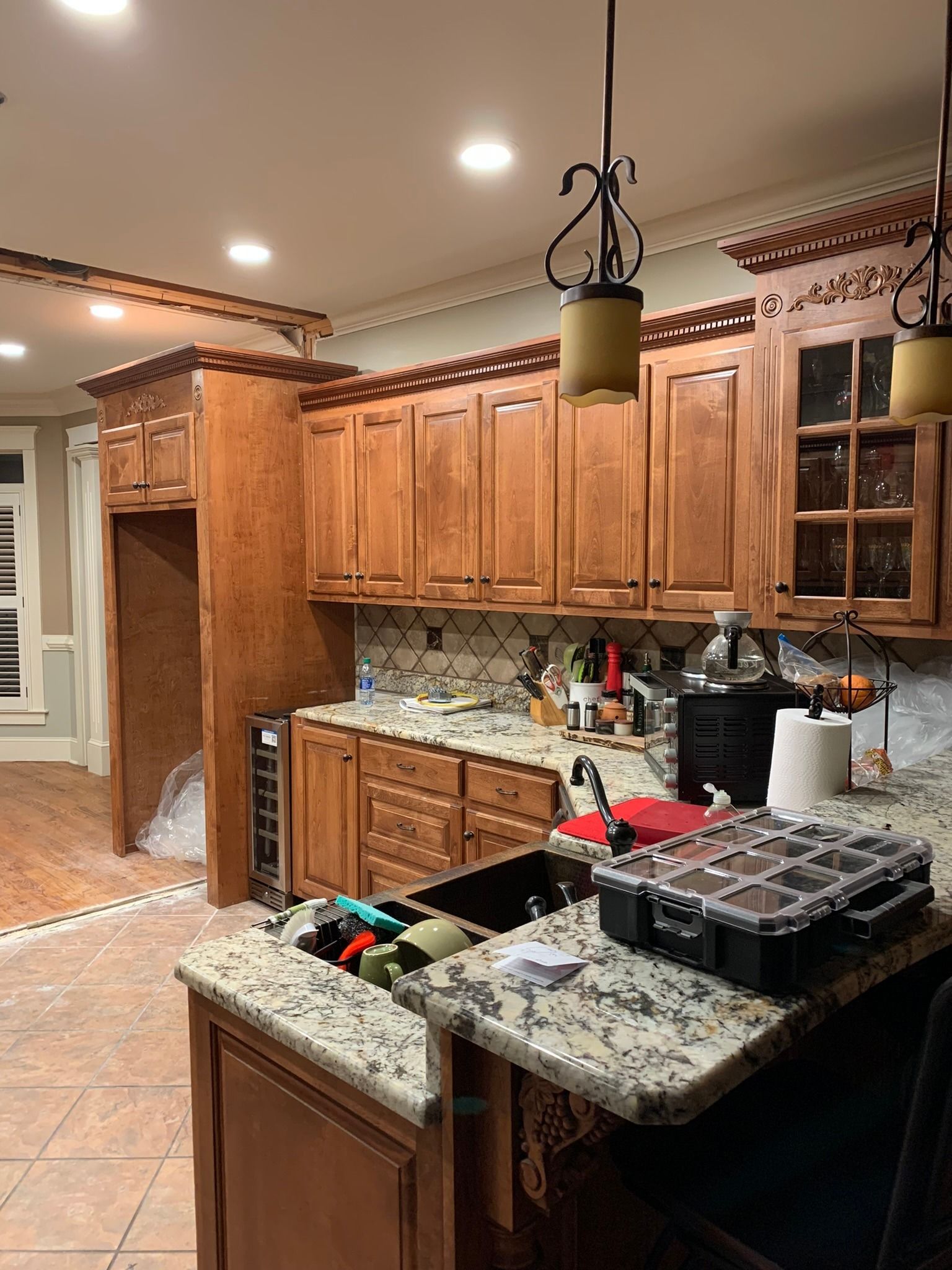 Kitchen under construction with light wood cabinets, granite countertops, and tools on island.