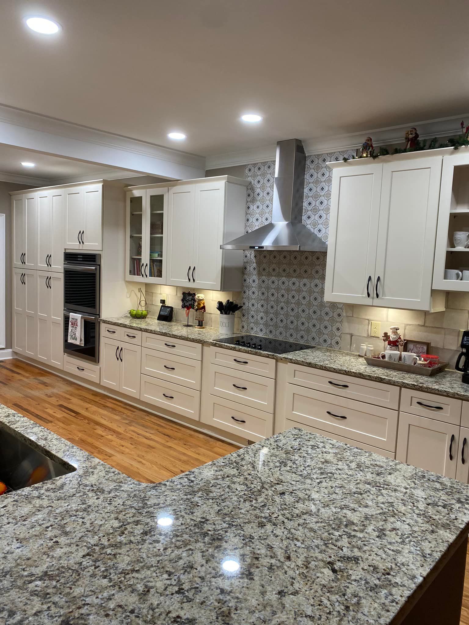 Modern kitchen with white cabinets, granite countertops, and stainless steel range hood.