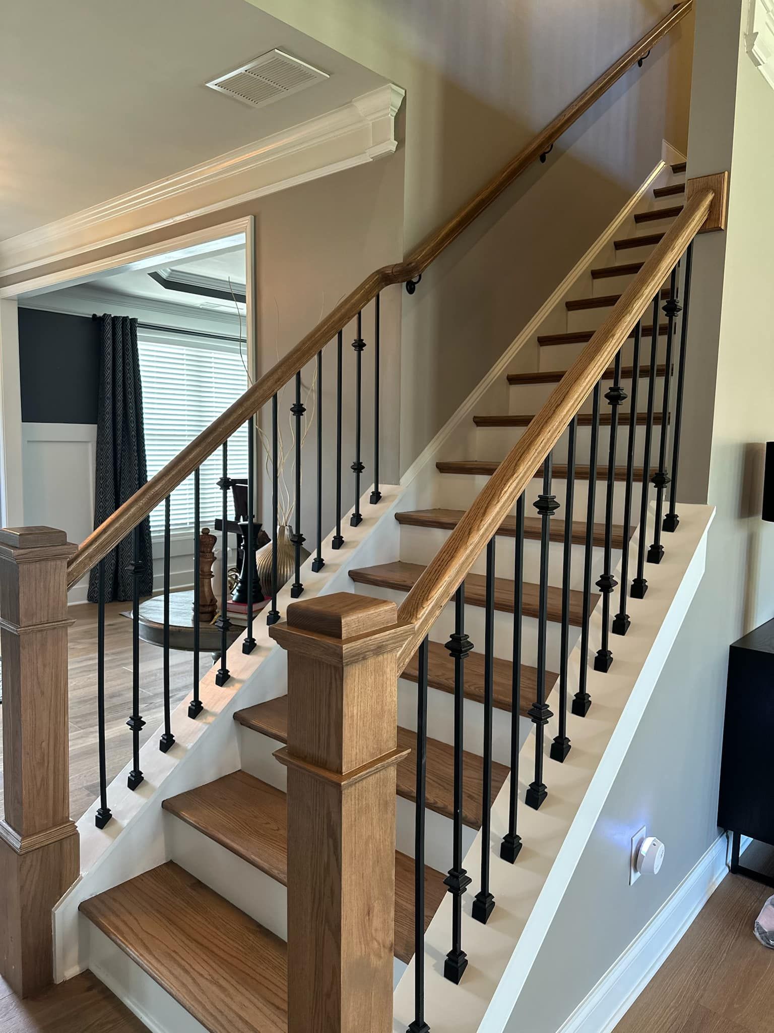 Wooden staircase with black metal balusters, leading up. White trim, neutral walls.
