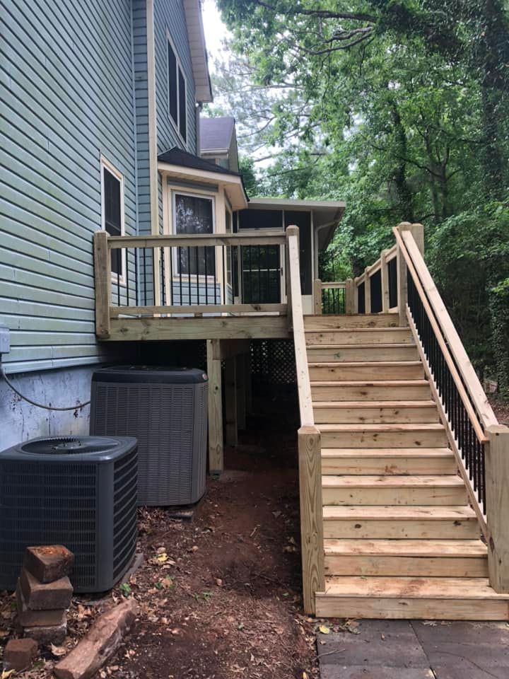 Wooden deck and stairs on a blue house, leading to a covered porch; AC units nearby.