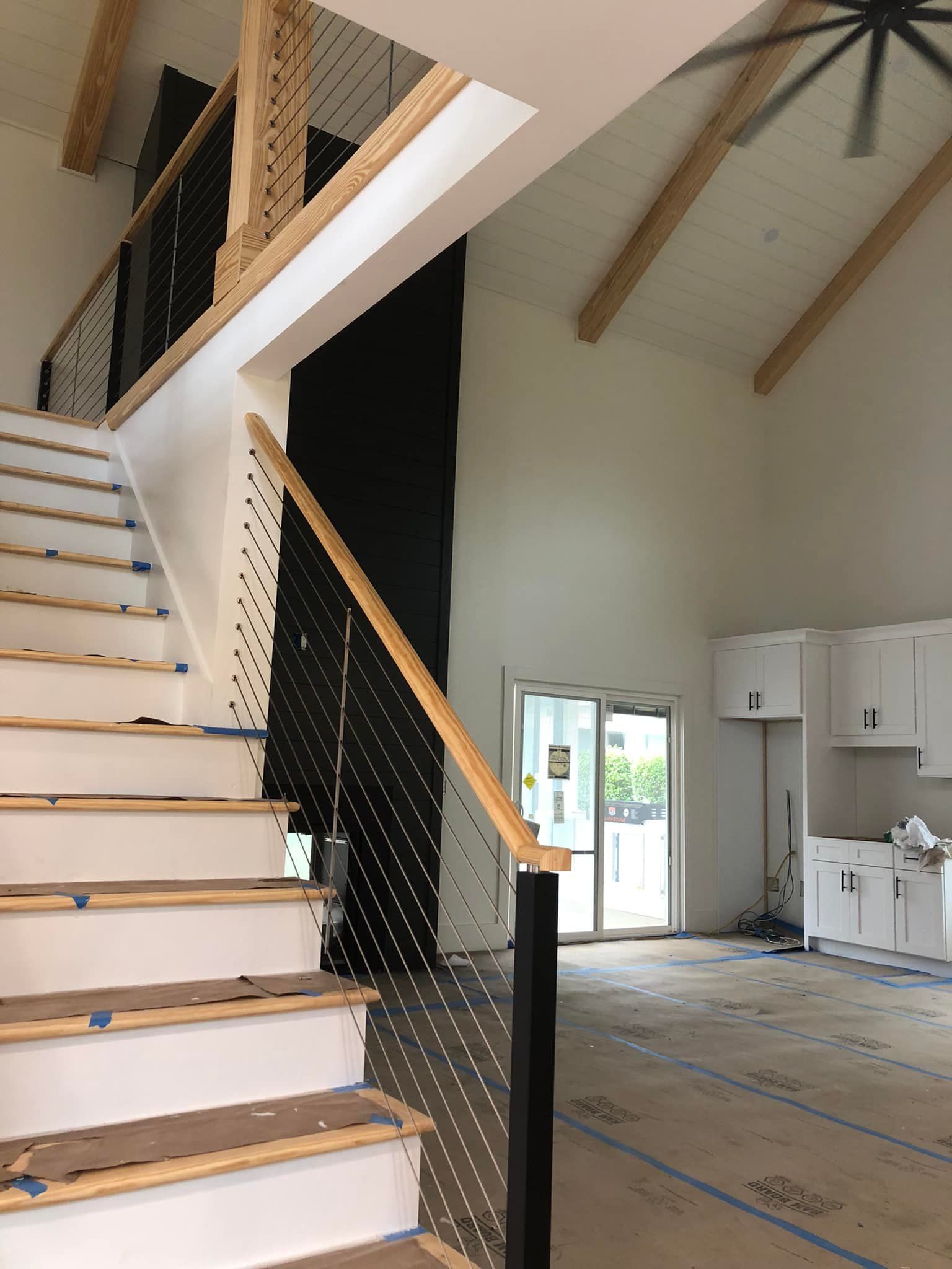 Interior view of a new home under construction with a staircase, high ceilings, and kitchen cabinets.