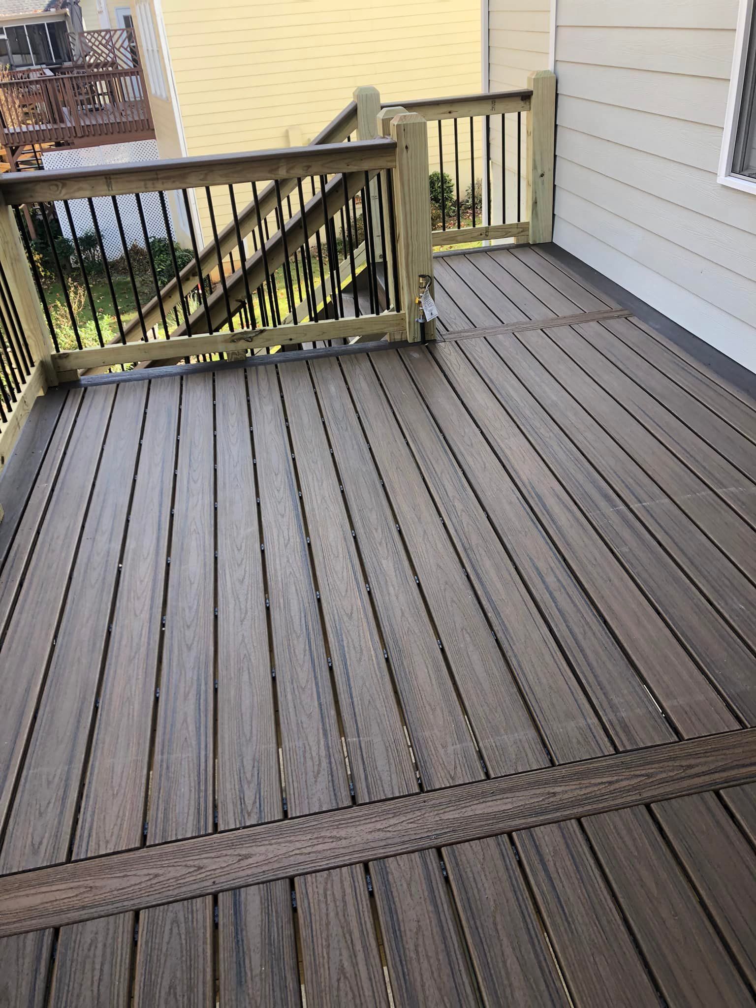 Wooden deck with railing. Dark brown boards and light brown railing posts.
