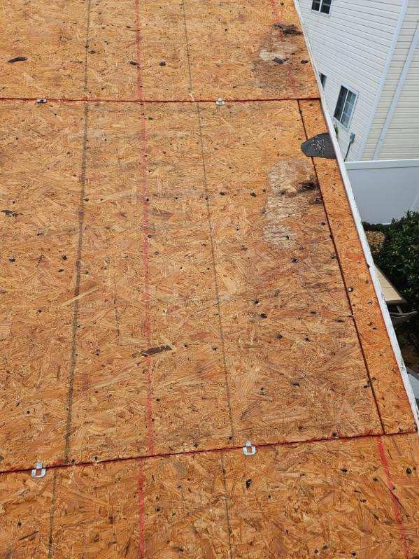 OSB roof sheathing with red grid lines, metal anchors, near a white building.