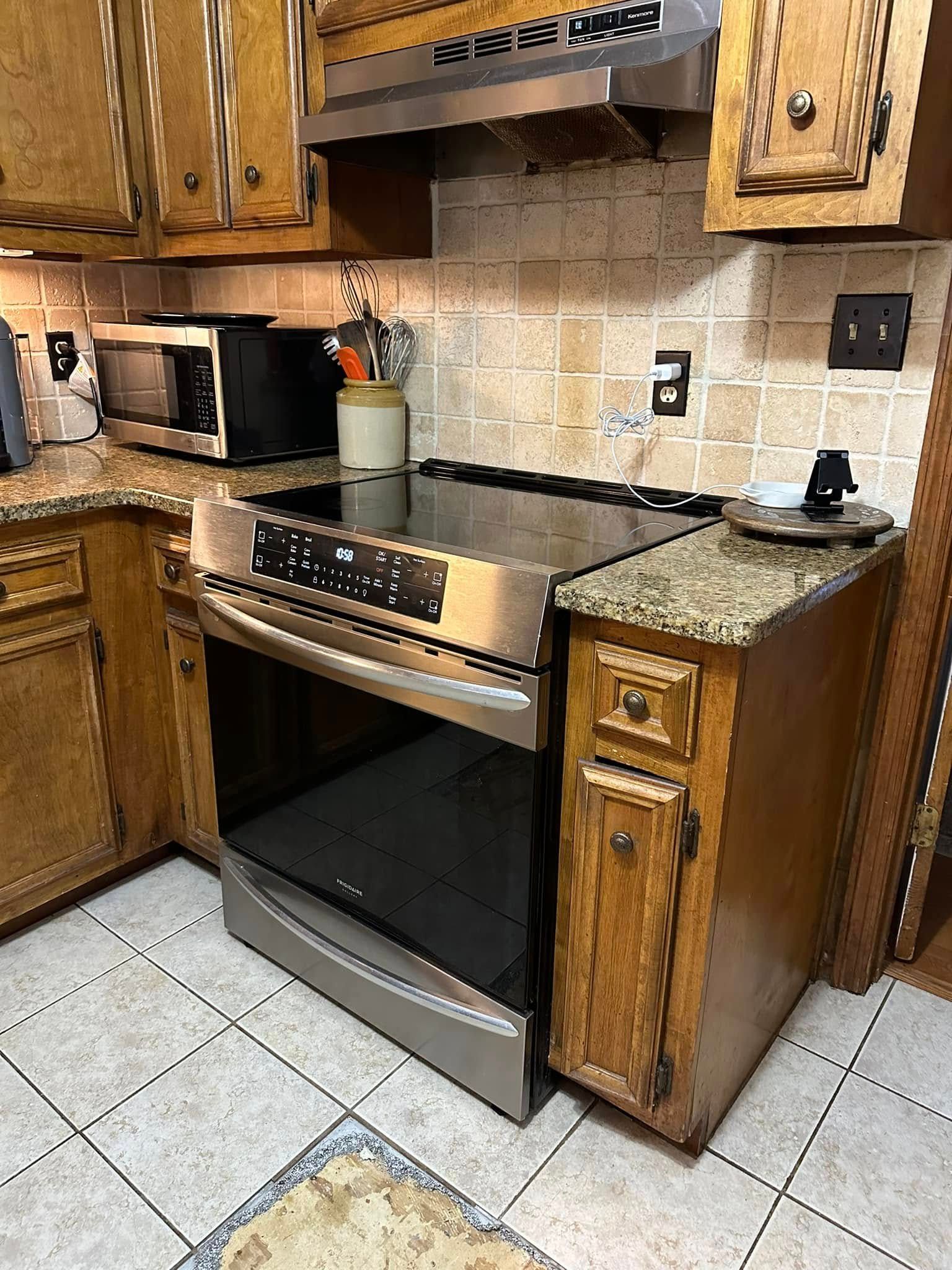 A kitchen with a stainless steel stove. Wooden cabinets and a granite countertop. Ceramic tile floor.