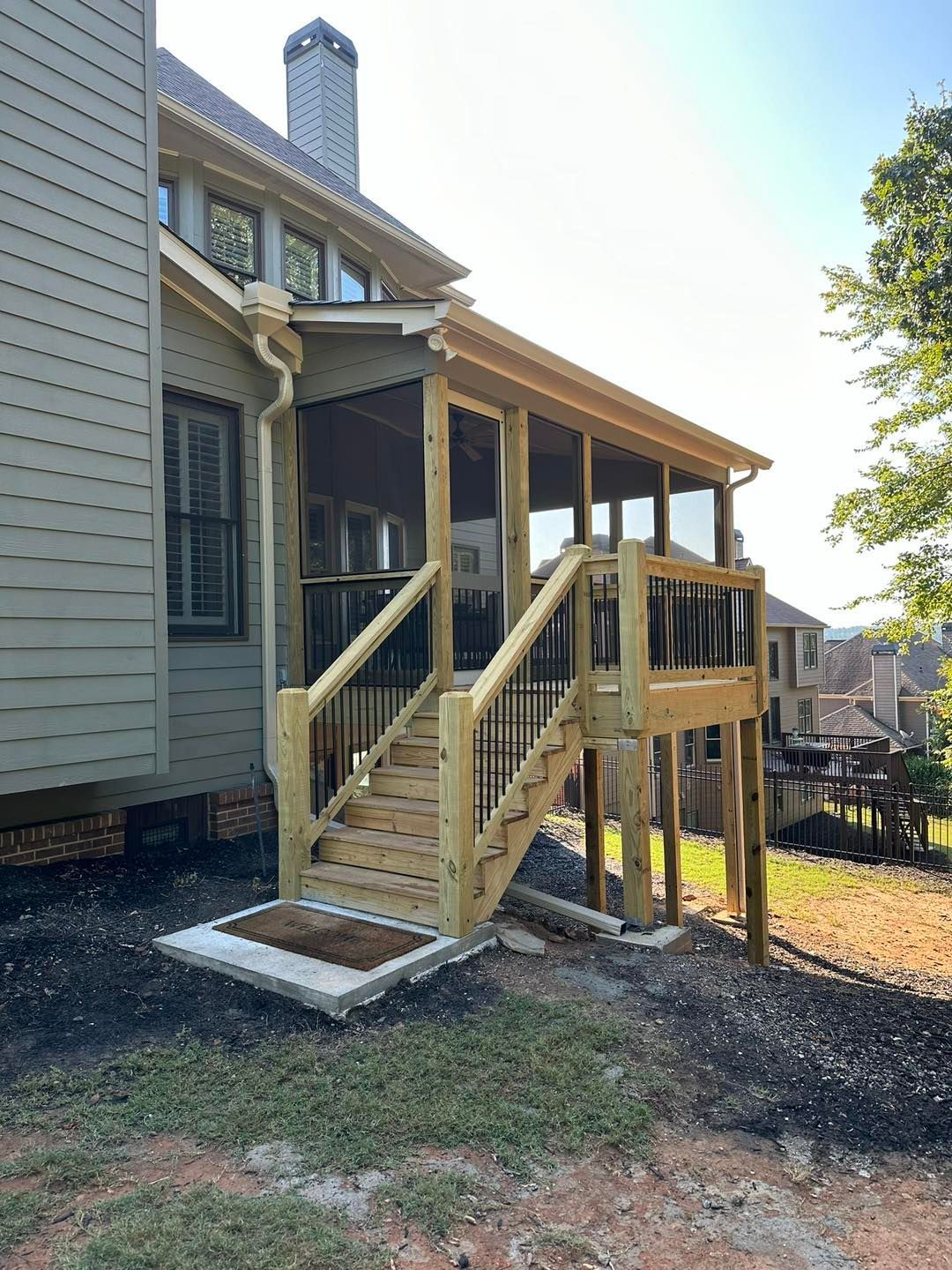 A newly constructed screened porch with stairs attached to a house with a green exterior.