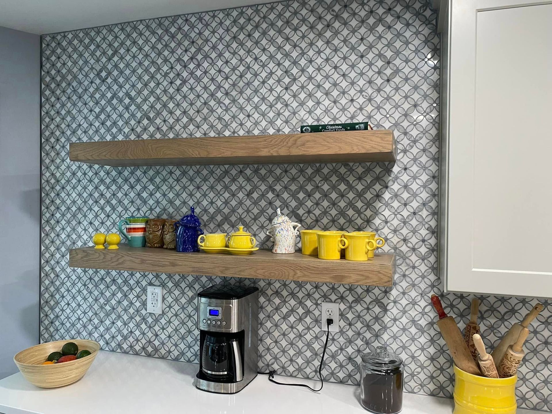 Kitchen backsplash with floating shelves holding mugs, a coffee maker, and other items.