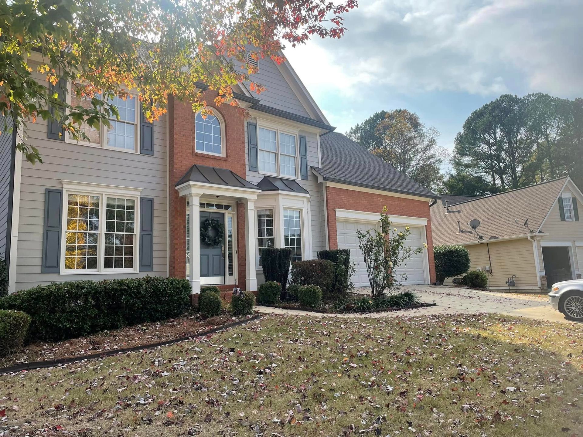 Two-story house with brick and siding, blue shutters, and a two-car garage. Overcast day.