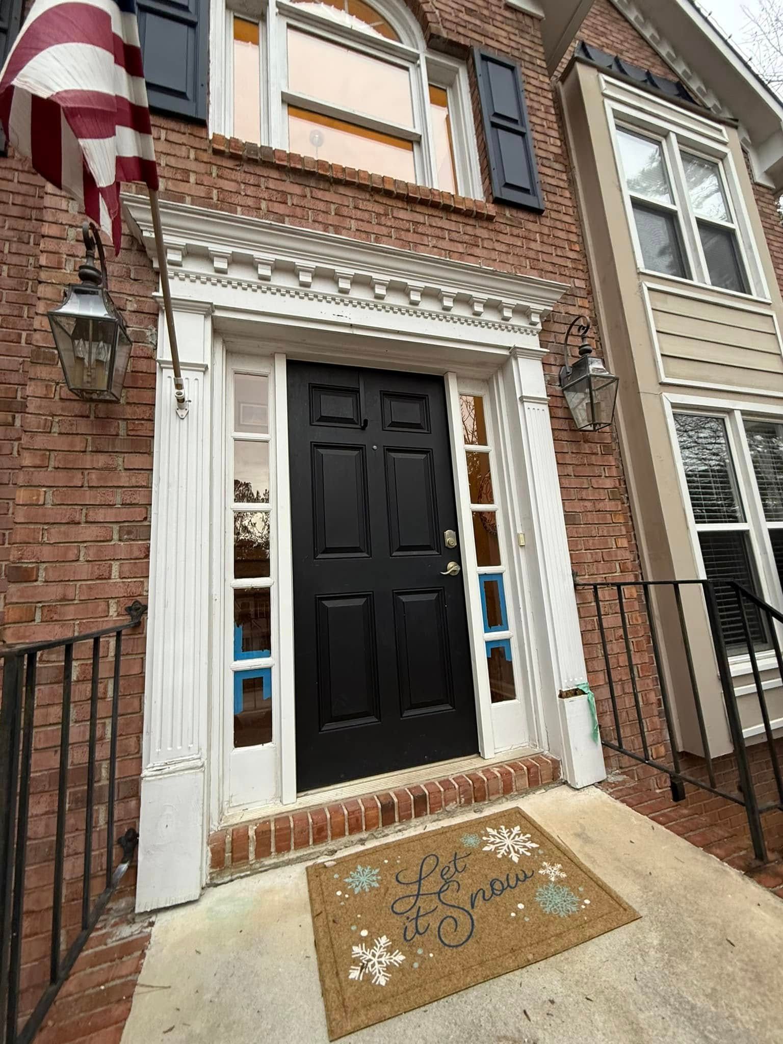 Brick building with black door, sidelights, white trim, American flag, welcome mat.