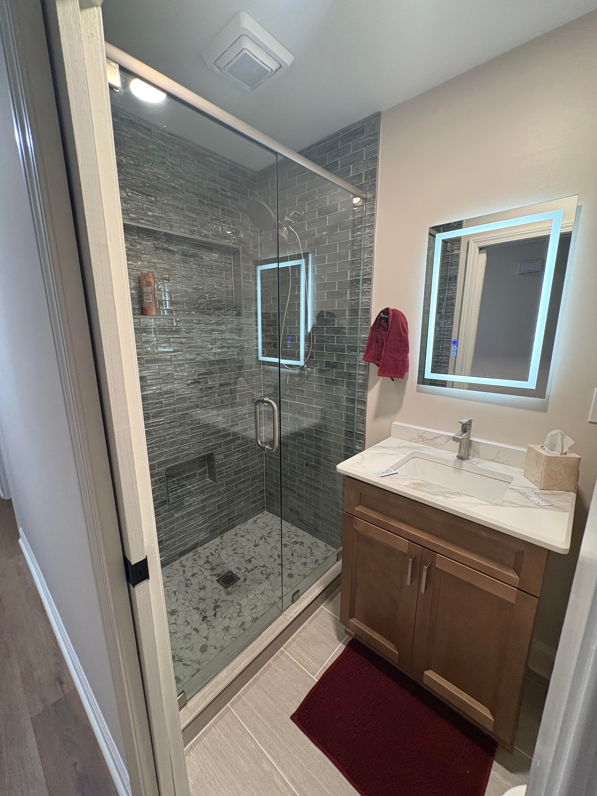 Small navy bathroom with a sink, mirror, shower, and toilet.