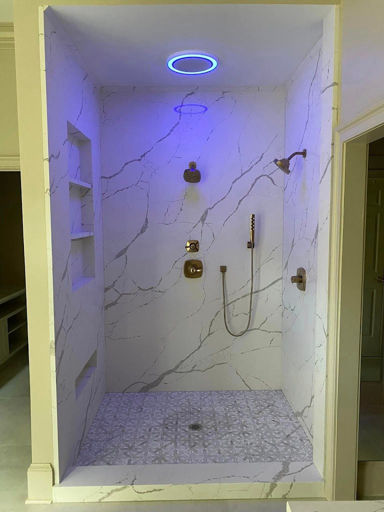 Luxurious marble shower with blue LED lighting and multiple shower heads.