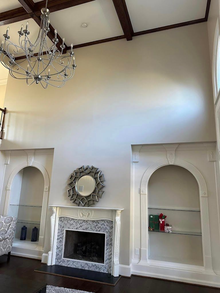 Living room with fireplace, built-in shelves, large chandelier, and tall walls painted light gray.