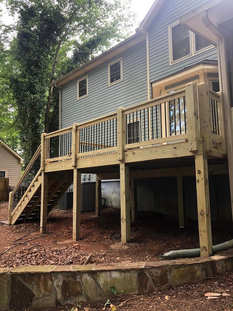 Wooden deck with stairs attached to a blue house, viewed from the yard.