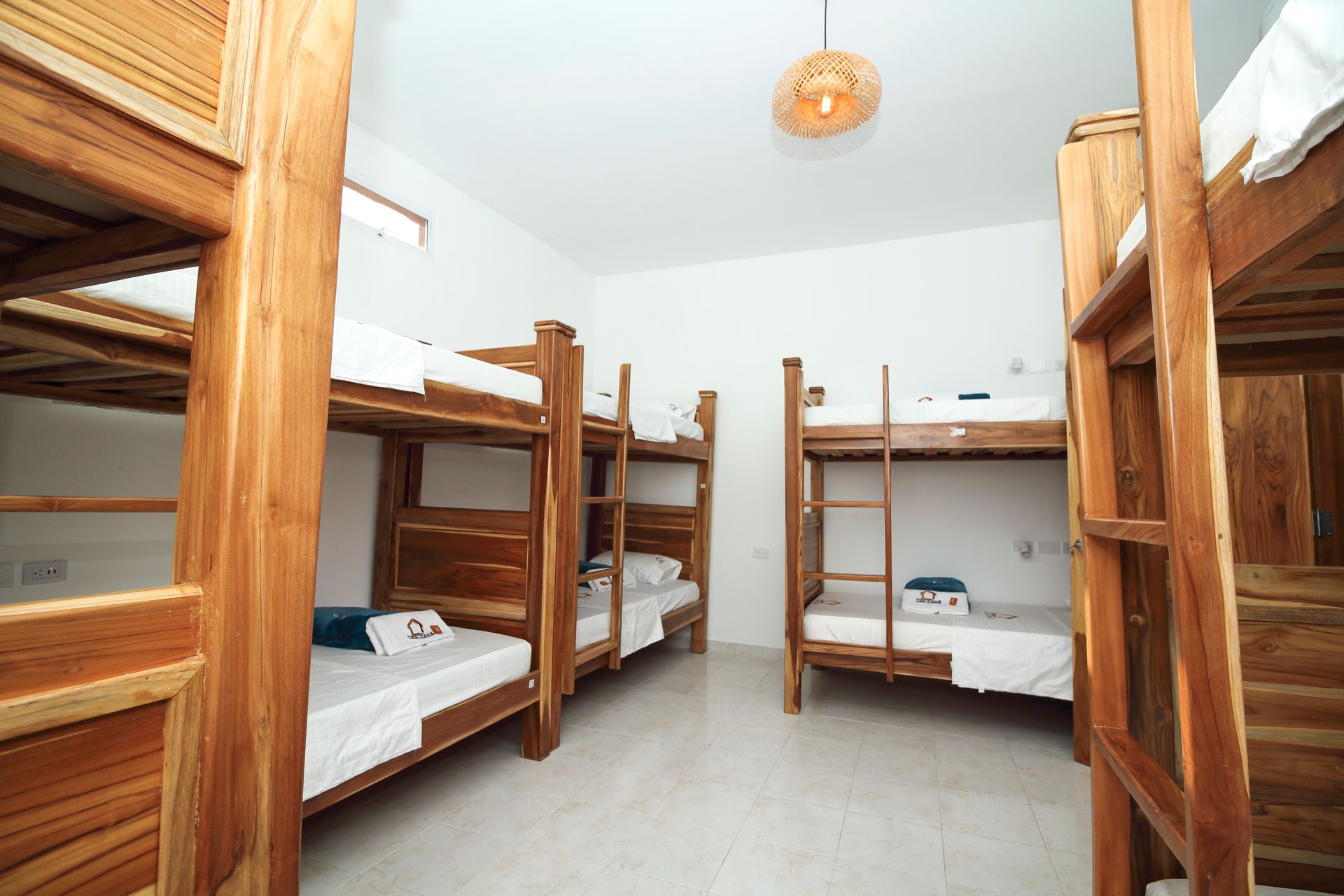 Una habitación de hostal bien iluminada con varias literas de madera.