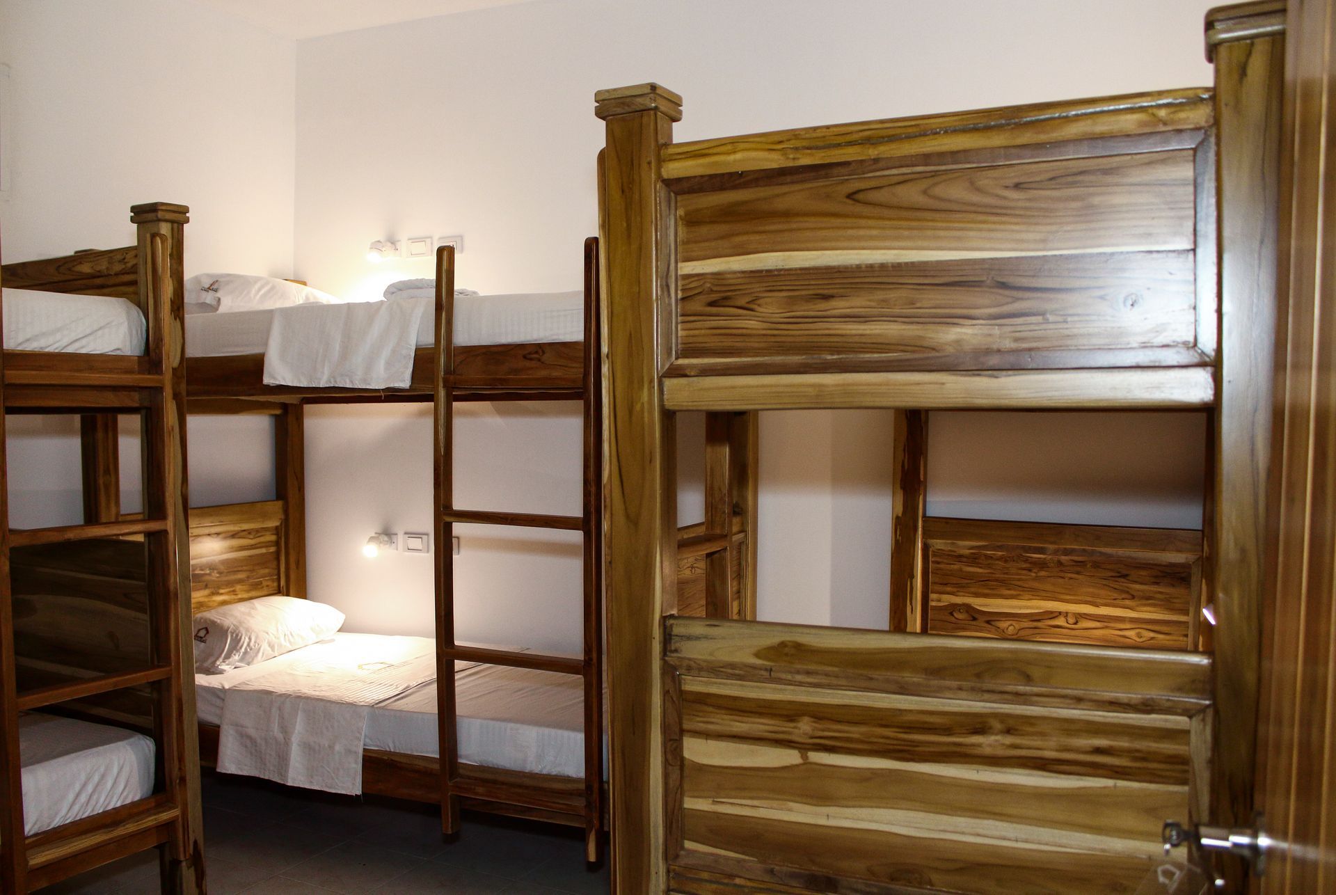 Literas de madera en una habitación con ropa de cama blanca.