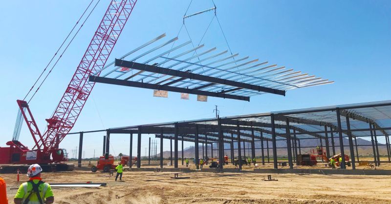 A construction site with a crane lifting a metal structure.