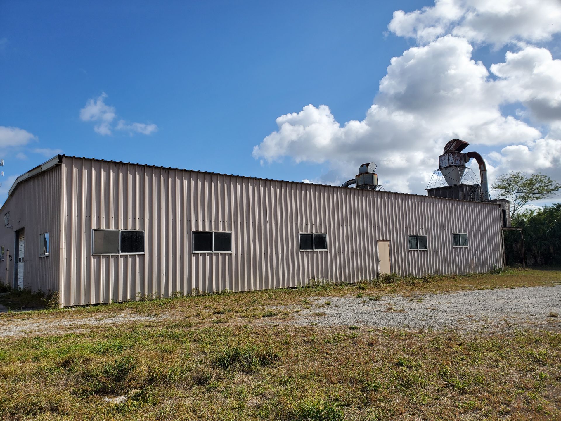A large building with a lot of windows is sitting in the middle of a field.