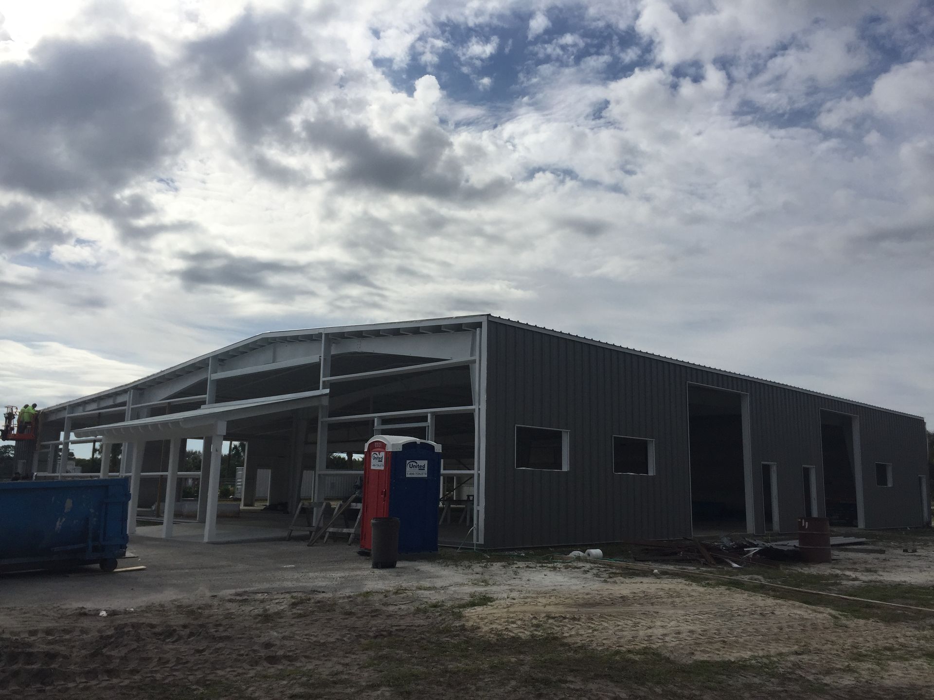 A large building under construction with a portable toilet in front of it.