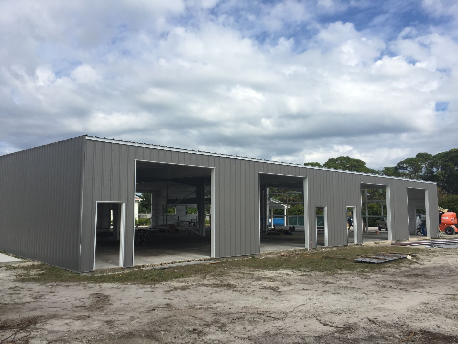 A large gray building is being built in a dirt field.