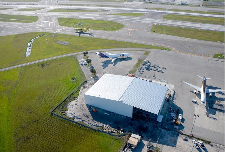 An aerial view of an airport with planes parked in front of a building.