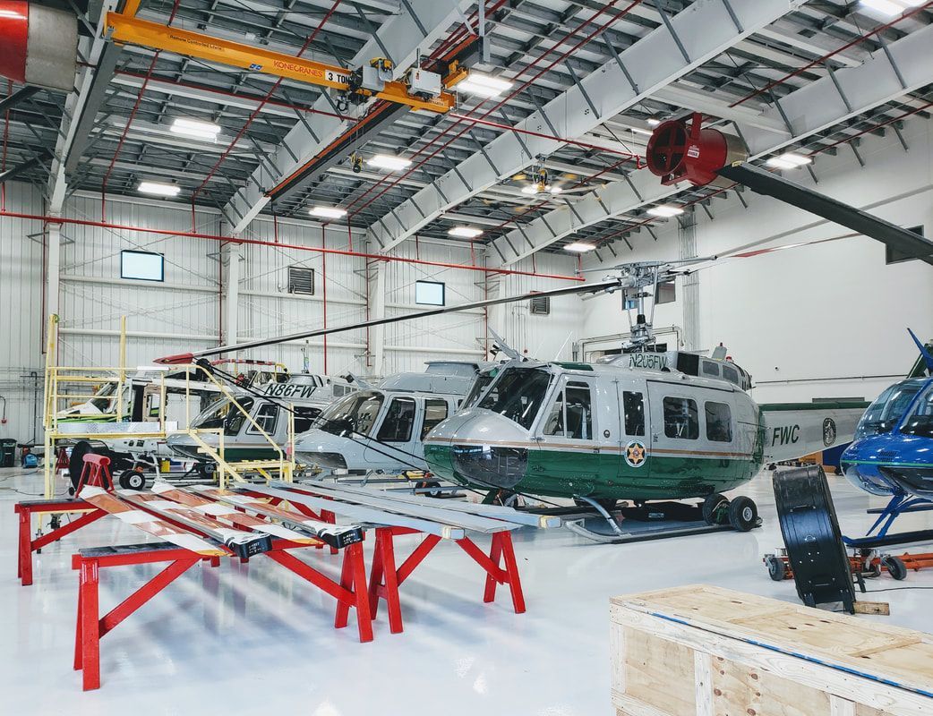 A green and white helicopter is parked in a hangar.