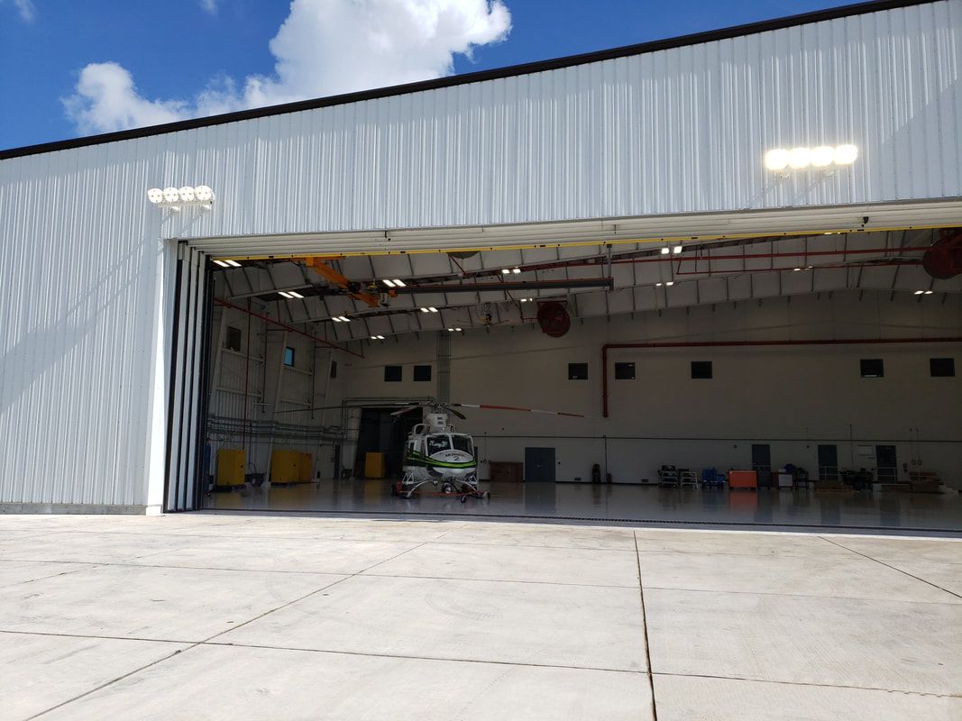 A plane is parked in a hangar with the door open