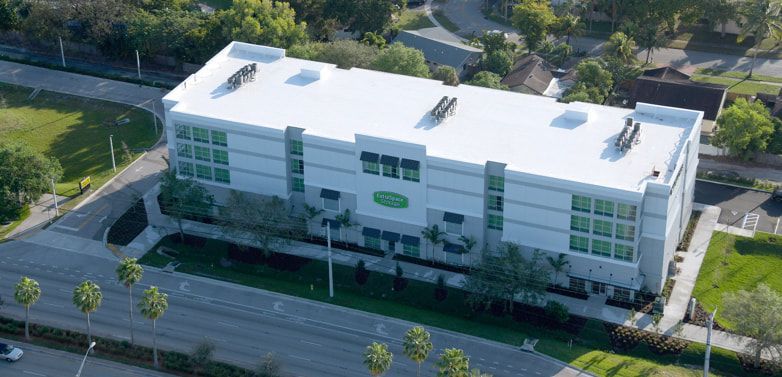 An aerial view of a large white building surrounded by trees and grass.