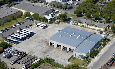 An aerial view of a warehouse with a lot of buses parked in front of it.